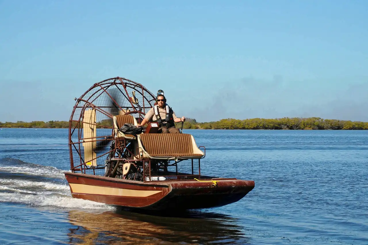 An airboat with a big fan crossing an open lake, trees on the far shore