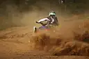 A rider on a quad bike kicking up dust on a sandy track