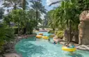 A turquoise lazy river with yellow tubes winding between rocks and palm trees
