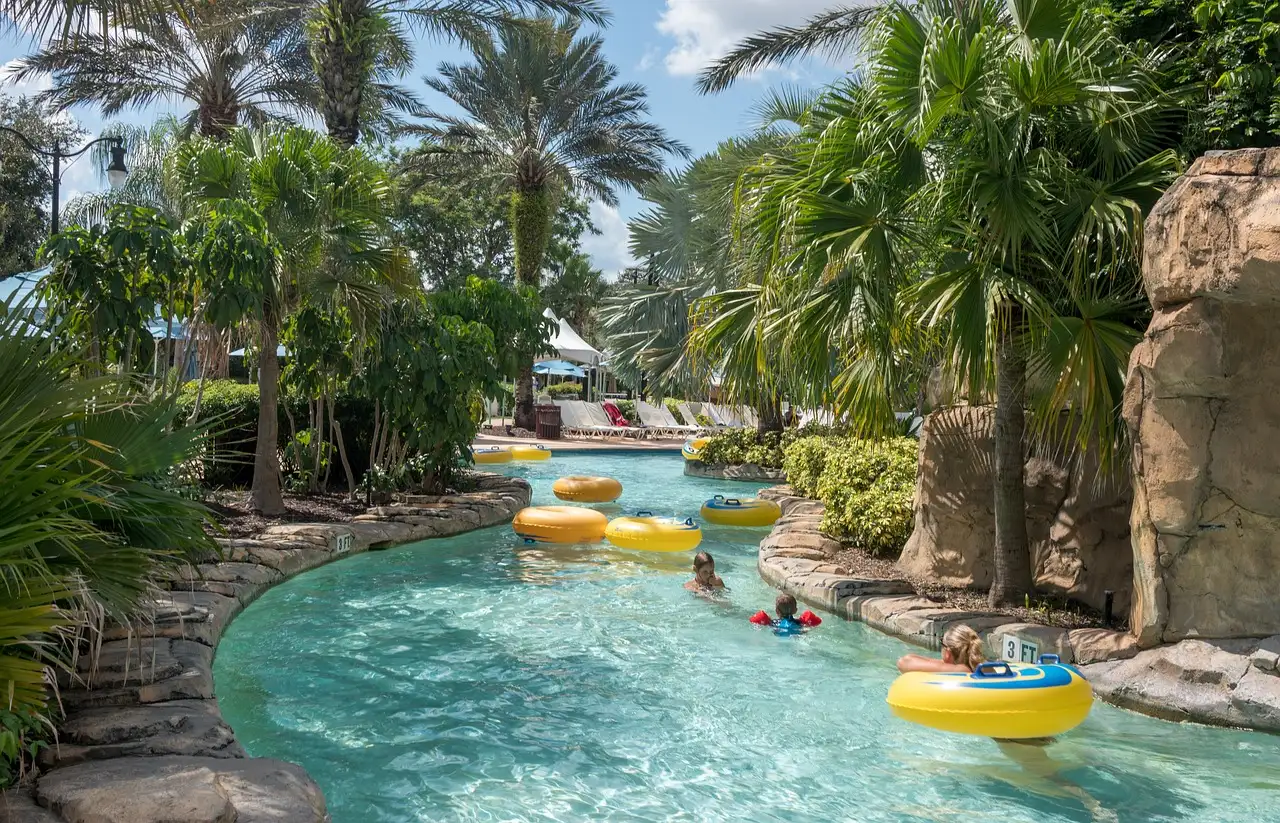 A turquoise lazy river with yellow tubes winding between rocks and palm trees