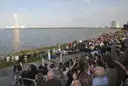 A rocket lifting off from Cape Canaveral across the water as a crowd watches