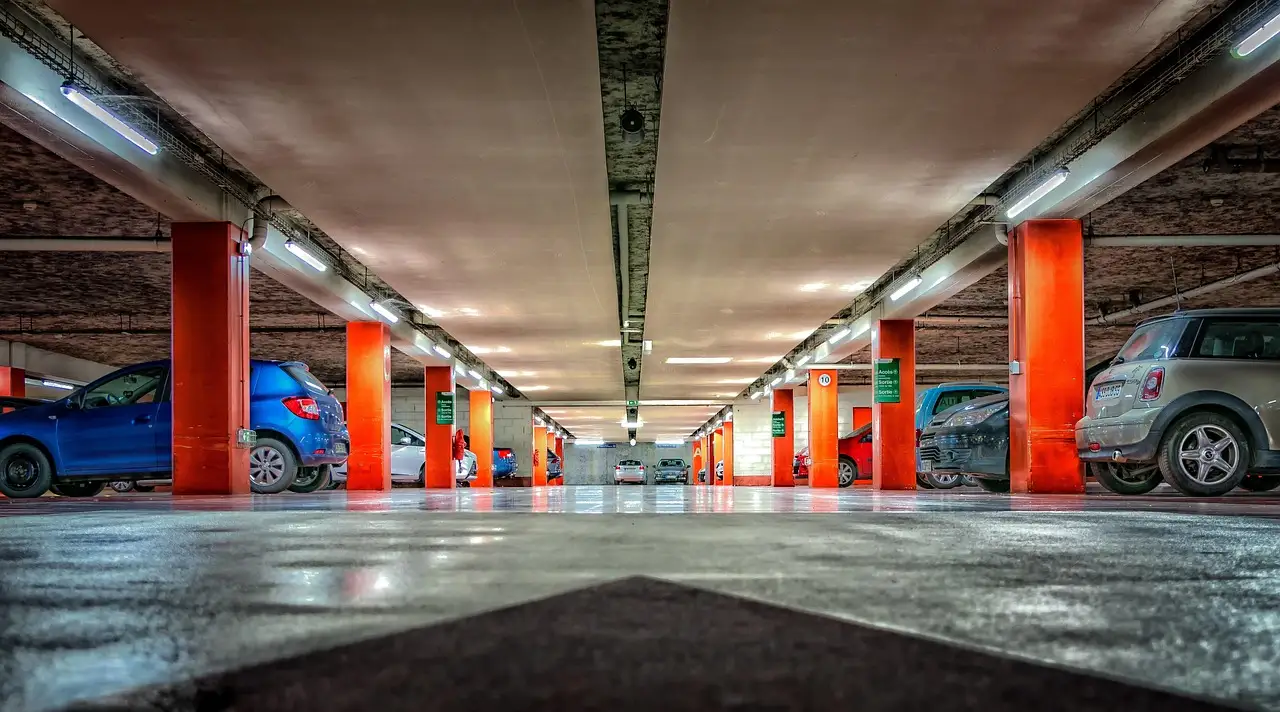 A wide multi-storey car park with red pillars and parked cars