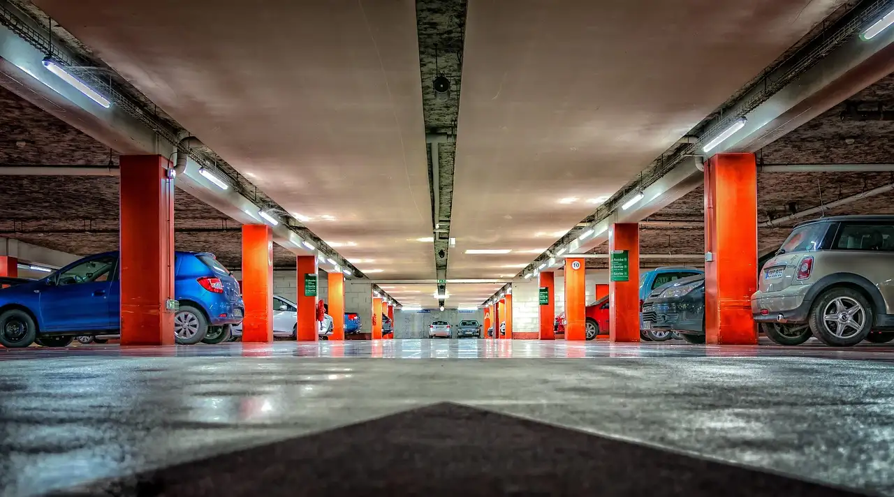 A wide multi-storey car park with red pillars and parked cars