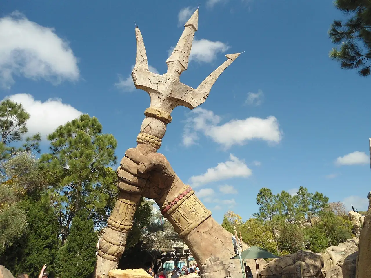A giant stone hand holding a trident in Islands of Adventure, under a blue sky