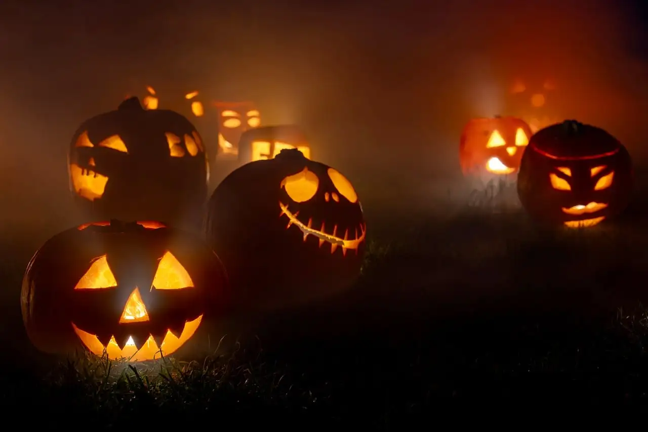 Carved jack-o'-lanterns glowing in thick fog at night
