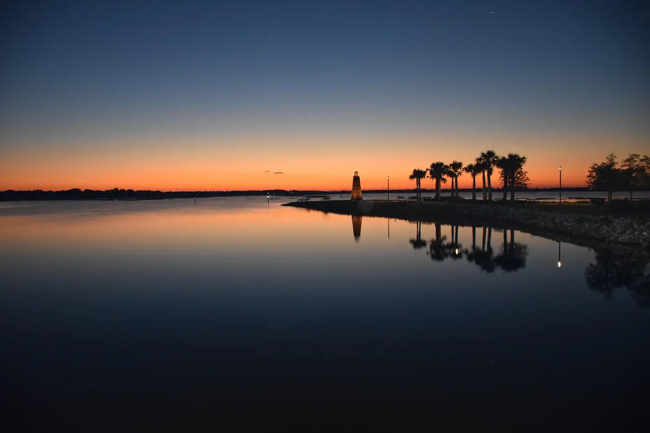 Sunrise over Lake Toho in Kissimmee, with palms and a small lighthouse on the shore