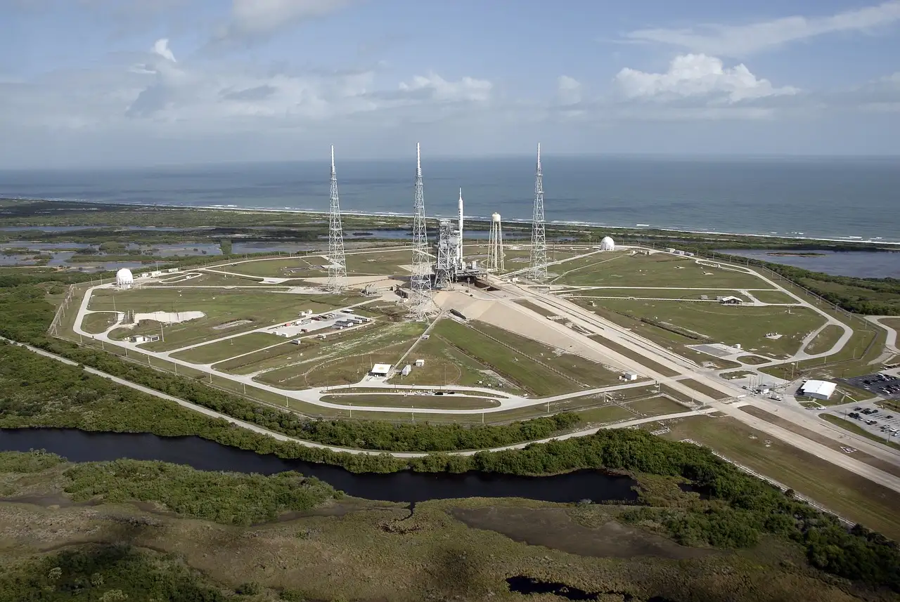An aerial view of a launch complex on the flat coast, with the sea behind