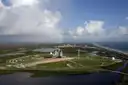 An aerial view of a launch pad by the coast, with green marsh around it