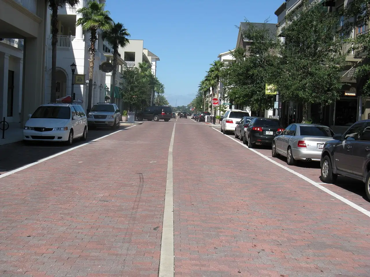 A brick street in Orlando lined with palm trees, shops and parked cars