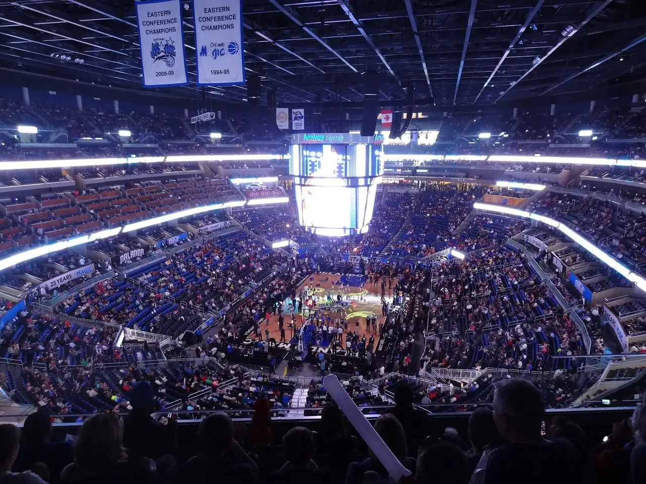 Fans in the stands of the Orlando Magic arena before a game, with Eastern Conference Champions banners hanging above the court