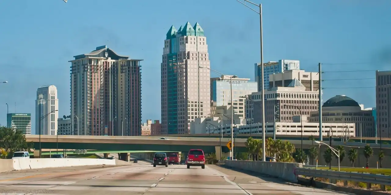 Downtown Orlando towers seen from a highway with a few cars on a clear day