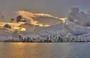 The Miami skyline across the water at sunset under heavy clouds