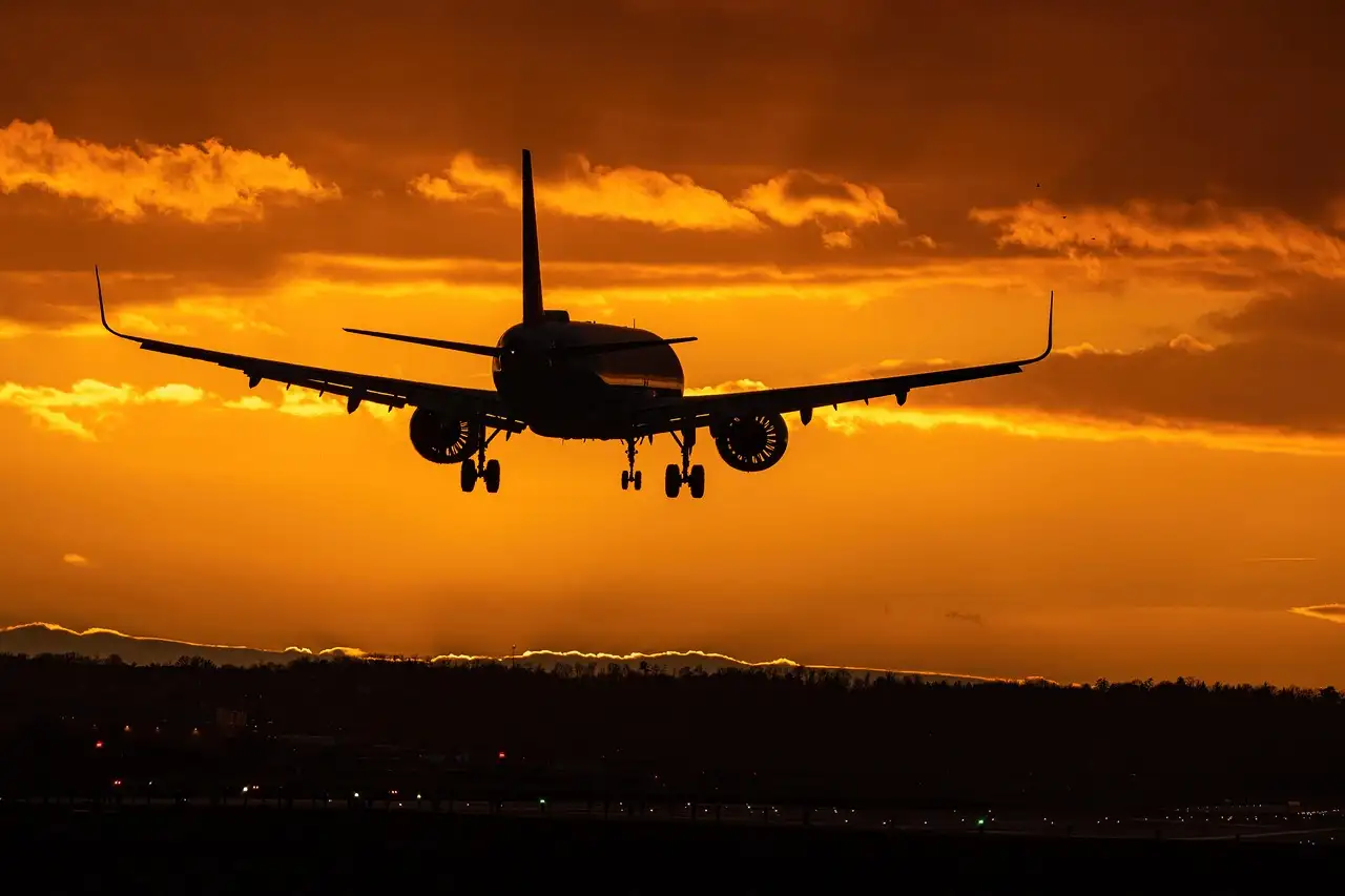 A passenger plane coming in to land against an orange sunset sky