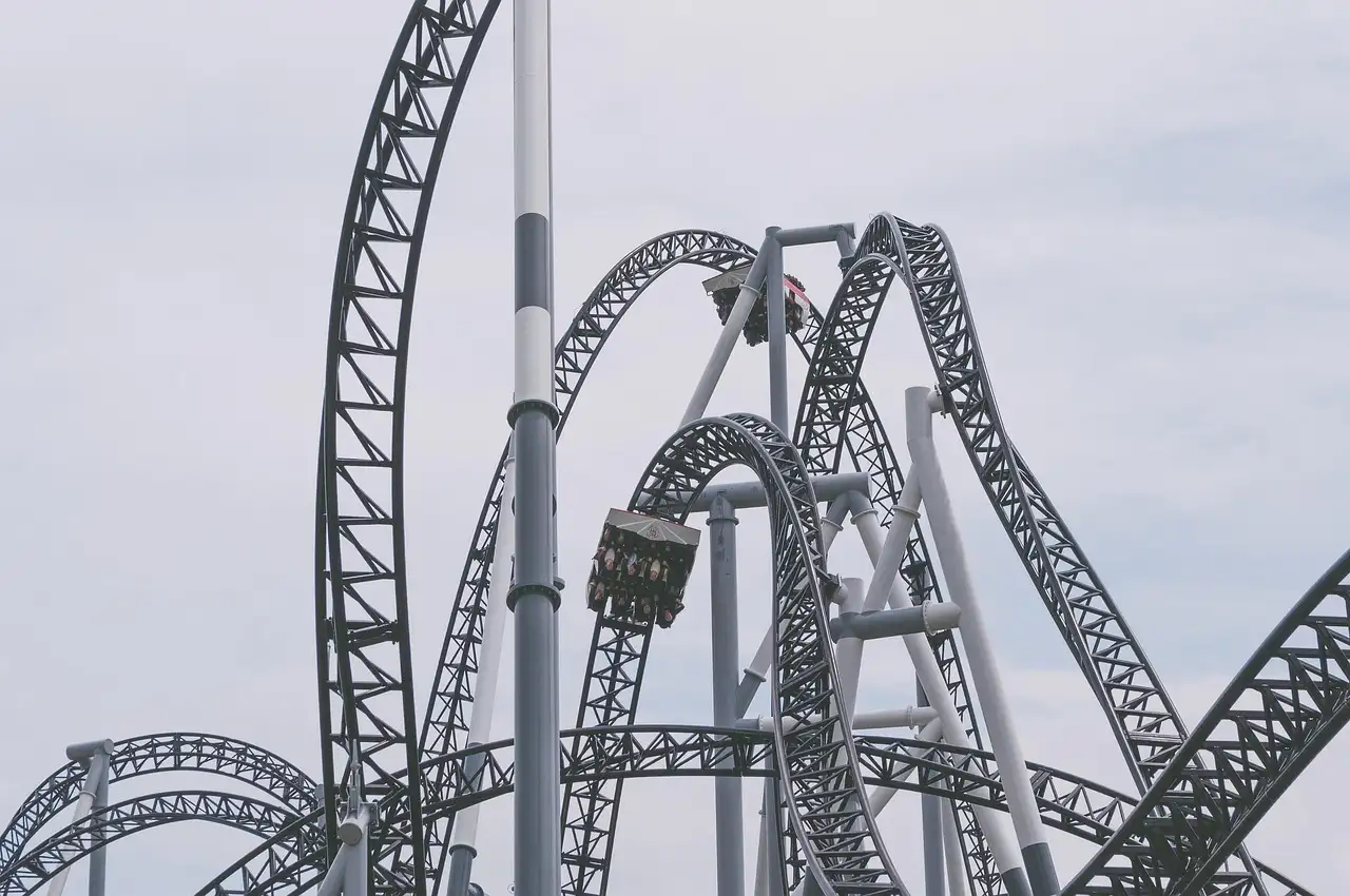 Grey steel roller coaster tracks twisting into loops against a white sky