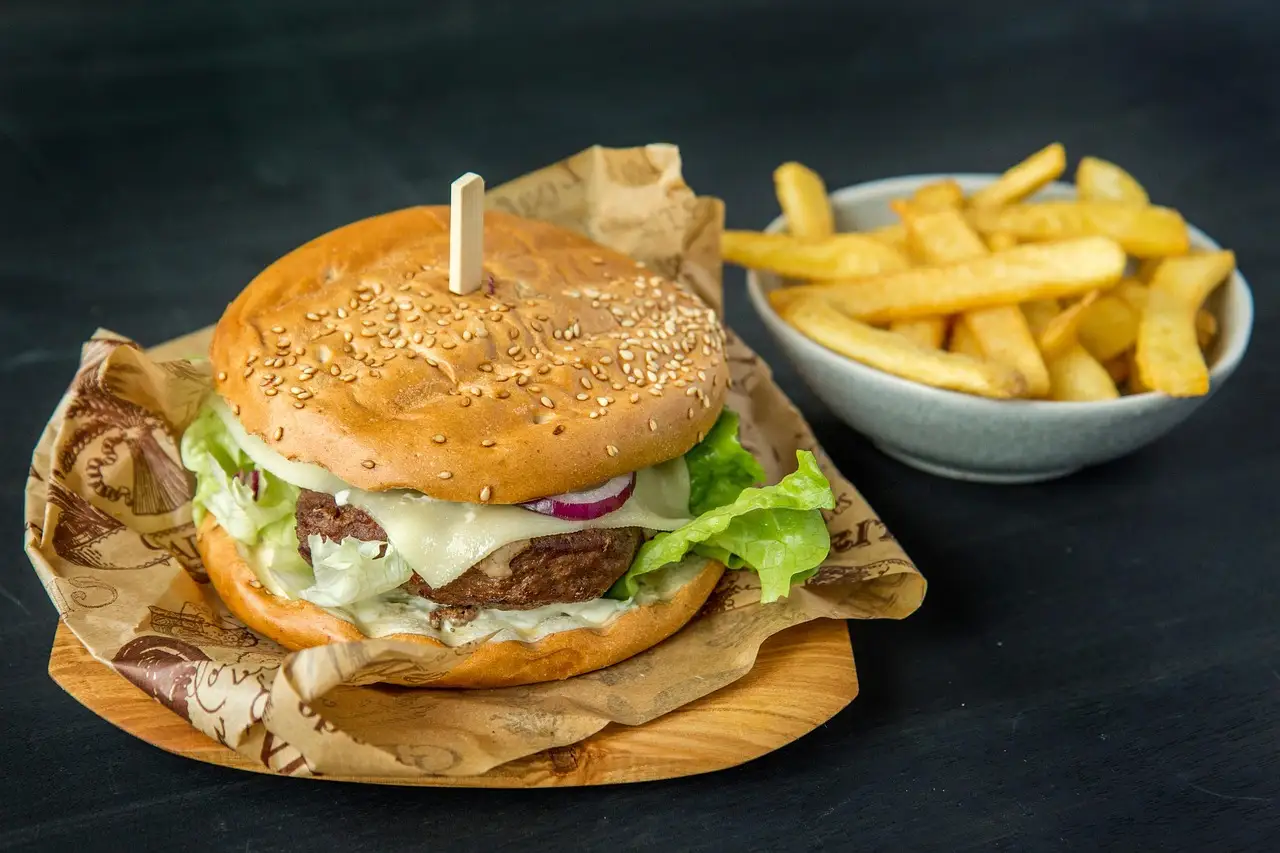 A burger and a bowl of fries served on paper on a table