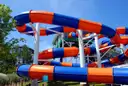 Blue and orange water slide tubes winding on posts under a blue sky